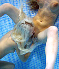 Two horny teenage babes playing with a doll in the water
