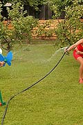 Two hot lesbian babes playing with a garden hose outside