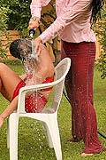 Two hot lesbian babes playing with a garden hose outside