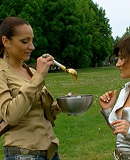 Two cute clothed hotties playing with liquid food outdoors