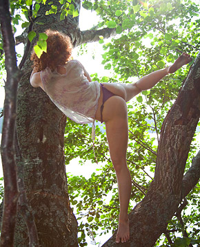 A pretty deranged teenage redhead hanging out in a tree