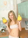 Long haired teen blonde posing and playing with toy fruit in the kitchen