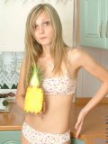 Long haired teen blonde posing and playing with toy fruit in the kitchen